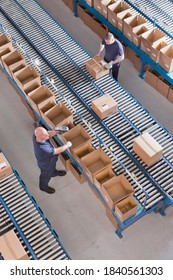 Vertical Top View Of Workers Scanning Boxes On Conveyor Belts At A Distribution Warehouse.