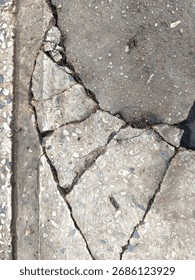 Vertical Top-Down View of Cracked and Broken Gray Asphalt and Concrete Pavement Texture with Exposed Gravel
