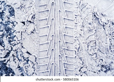 Vertical traces of car tires in the snow on the asphalt. Close up view from above, image in the blue toning