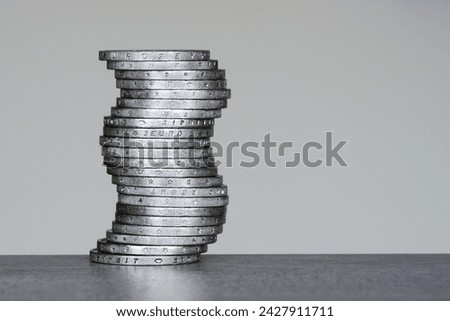 Vertical unstable curved pile of two euro coins on a grey background, future balance concept