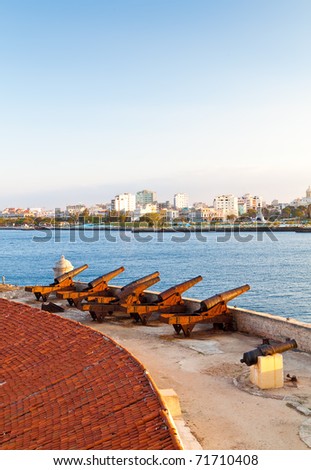Vertical view of a battery of cannons facing the bay of Havana with a view of the old city