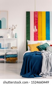 Vertical View Of Bed With Pillows And Blanket Next To Book Shelf With Books And Vases