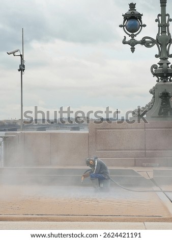 Vertical view the blast cleaning. An unrecognizable man at work at the bridge construction site, working in the dust. The dusty construction that floats in the air. Saint-Petersburg. 