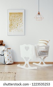 Vertical View Of Bright Baby Nursery With White Crib And Golden Painting On The Empty White Wall