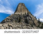 Vertical view of Devils Tower, Wyoming under a dramatic blue sky with white clouds