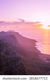 Vertical view of a dramatic sunset with pink and orange clouds over the silhouetted Cape Peninsula mountains and coastline, Western Cape, South Africa