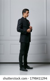 Vertical View. Elegant Young Fashion Man Adjusting His Suit While Looking To His Side, On White Background.