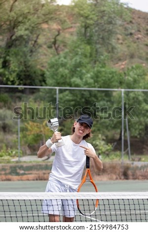 vertical view of excited young teenager pointing his new champion winning cup holded on his hand
