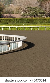 Vertical View Of Horse Racing Track With White Fences And Dirt Track Around The Turn.