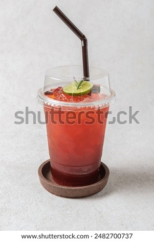 Vertical view of  Iced Lime Tea in a plastic glass, Includes a straw and a refreshing tropical drink menu.