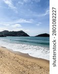 Vertical view of La Concha beach in San Sebastian, Basque Country. Soft overcast light over turquoise bay with Monte Igueldo hill and Santa Clara Island in background.