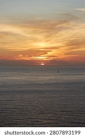 Vertical view of the last sun rays setting over the ocean horizon