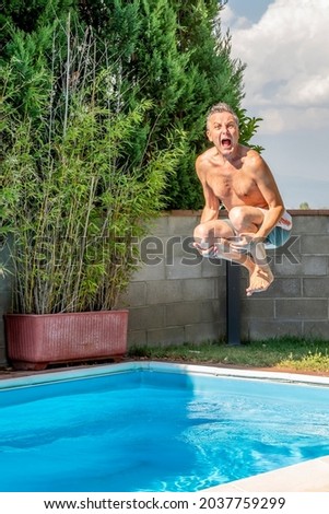 Vertical view of a middle-aged white man diving into a swimming pool, cannonball style, while screaming like crazy