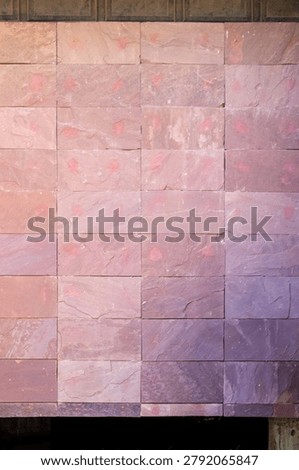 Vertical view of a rectangular red sandstone tile wall texture showing natural variations in color and stone surface.