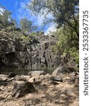 A vertical view of a river surrounded by rocks and vegetation, on a sunny day with blue sky in Cedar Creek, Queensland, Australia
