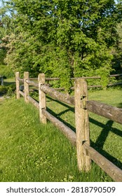 Vertical view of a rustic log fence surrounded by a lush green landscape, showcasing weathered wood, natural textures, and a peaceful rural setting