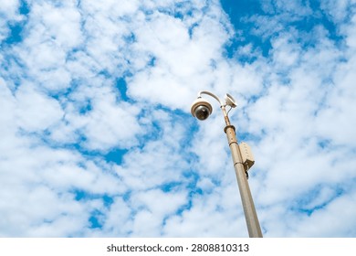 Vertical view of a seaside remote CCTV dome camera seen against a summer sky. The salt air has called rust of the lamppost. In an area for low level crime and anti social behaviour.