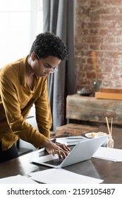 Vertical view thoughtful African woman lean over desk working on laptop, analyzing, thinks about problem solution, make task review, do paperwork, prepare report at workplace. Tech, workflow concept - Shutterstock ID 2159105487