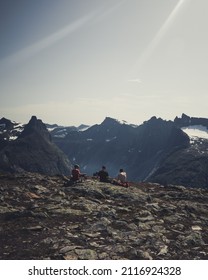 A Vertical View Of Three Mountain Climbers Resting On The Rocks On The Mountain And Enjoying The View