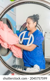 Vertical View Through The Door Of A Washing Machine Of A Woman Picking Up A Sheet In A Laundry