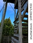 A vertical view from the tower at Parnell Tower State Park at Plymouth Wisconsin showing part of the structure along with a beautiful vista of trees from a lower observation deck with light clouds. 