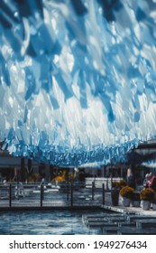 A Vertical View Of An Urban Public Area With Blue And White Tapes Hanging From The Top A Blue-tiled Pool In The Bottom And Bridge In A Defocused Background, Shallow Depth Of Field, Selective Focus