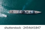 vertical view of warship sailing in calm blue waters  accompanied by small vessel