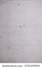 Vertical view of a weathered light grey cement surface showing subtle horizontal striations, minor cracks, and small porous holes.
