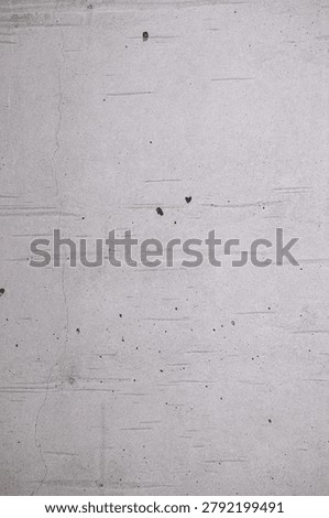 Vertical view of a weathered light grey cement surface showing subtle horizontal striations, minor cracks, and small porous holes.