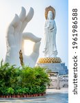 Vertical view of white hand statue and Guanyin statue in the background at Nanshan Buddhism cultural park temple in Sanya Hainan island China (translation: Nanshan temple Guanyin above sea )