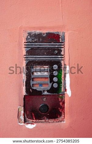 Vertical vintage intercom on dark pink wall of old apartment building