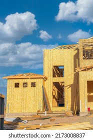 Vertical White Puffy Clouds Unfinished House Structure With Timber Frame And Cork Wall Insulation. Exterior Of An Under Construction Two-storey House Against The Clear Blue Sky Background.