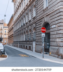 Vertical wide angle eye level shot of a narrow Budapest street featuring a yellow bicycle lane marking, a no-entry sign, and classic stone facades