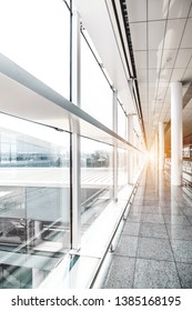 A Vertical Wide-angle View Of A Long Bright Corridor Of A Transport Terminal Building: An Airport Or A Railway Station Depot, With Plenty Of Columns, Bright Window Facade, Diminishing Perspective