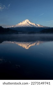 Vertical wide-angle view of a snow capped mountain reflected in an alpine lake.