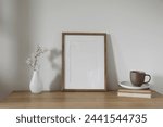 Vertical wooden picture frame, poster mockup. Spring, easter composition. Asian interior, home office still life. Artistic display. Blooming cherry plum tree branches in glass vase. Wooden table.