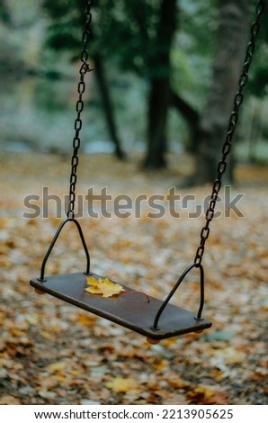 Vertical yellow maple leaf on swing in the park
