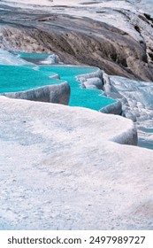 A vertically framed image capturing the elegance of turquoise water pools surrounded by mineral-rich terraces, offering a unique perspective of this awe-inspiring natural wonder.