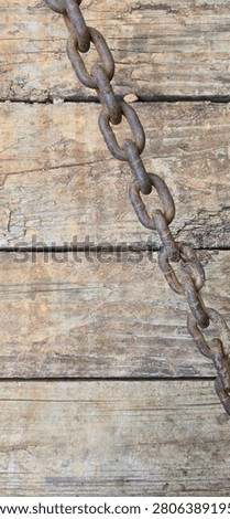 Vertically Oriented, Close-Up Photograph Showing A Rusted Metal Chain Lying Diagonally Across A Weathered Wooden Plank Surface