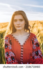 vertikal shot of young beautiful woman wearing ukrainian traditional embroidered dress in wheat field during sunset. Stand with Ukraine