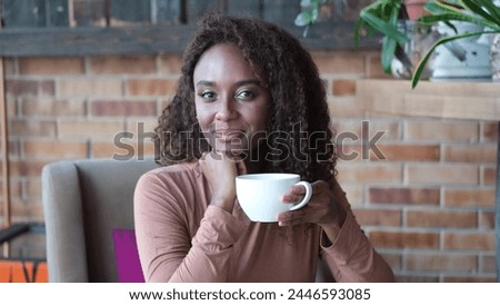 A very beautiful African American woman is sitting at a table in a cafe with a cup of coffee or tea. Stock photo © 