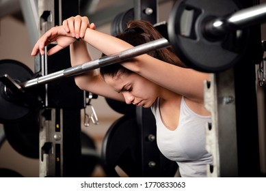 Very beautiful teenage girl resting and getting motivated between sets of barbell squats in gym. She keeps her eyes closed.  - Powered by Shutterstock