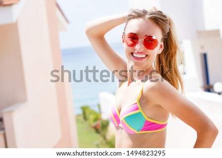 Very beautiful white woman in stylish red sunglasses posing on a sea background of a hotel of the sea and tropics