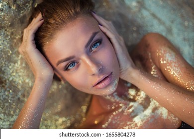 very beautiful woman with incredible blue eyes lies on the golden sand. Sensual portrait of amazing girl wet hair. Tan beach vacation spa. Sexy model portrait close-up. Glamor sparkles on body