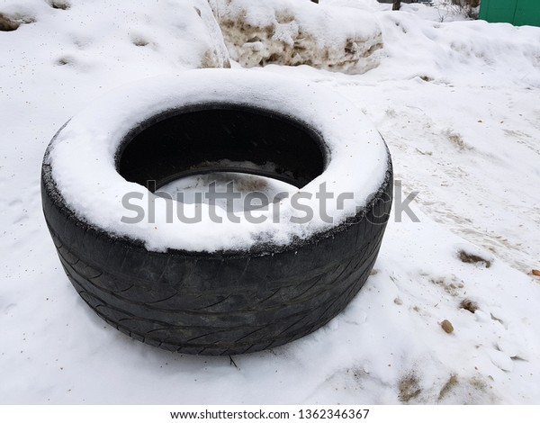 Very big old car\
tire in the snow in winter