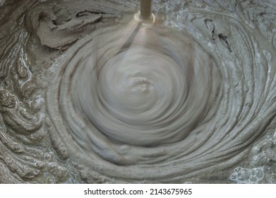 Very blurry image of tool rotation in cement mortar. The process of mixing concrete with a construction mixer. A mixture of sand and cement for construction. Selective focus