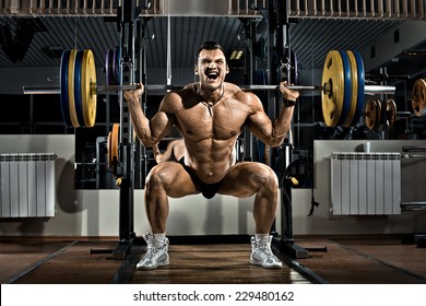 Very Brawny Guy Bodybuilder ,  Execute Exercise Squatting With Weight, In Gym