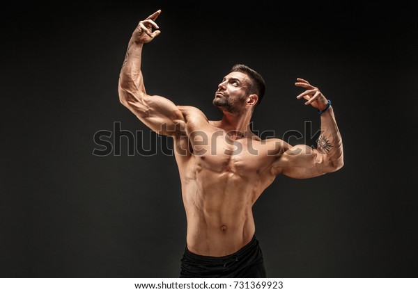 ボディビルダーのポーズをとっているとても屈強な男 美しいスポーティー男性の力 フィットネス筋肉質の男性 の写真素材 今すぐ編集