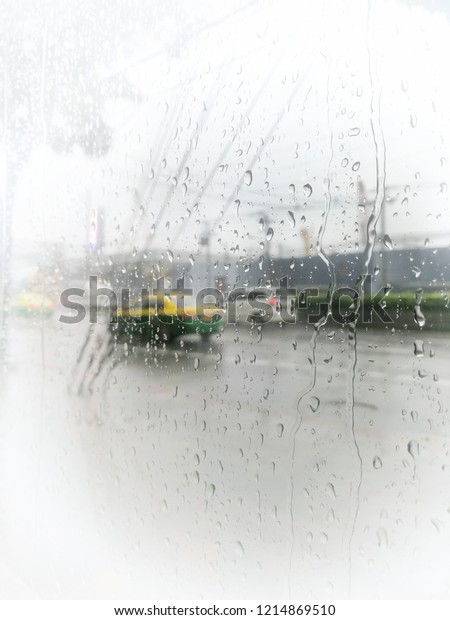 very bright, soft shot of rain drops
falling down on glass window of building beside city road, implying
someone staying indoor until the rain lets
up