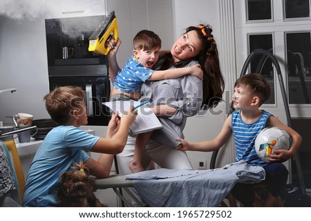A very busy mother. A very busy woman. A mother who does several things at the same time. A woman who makes several things at the same time. A woman irons and spands time with her children.